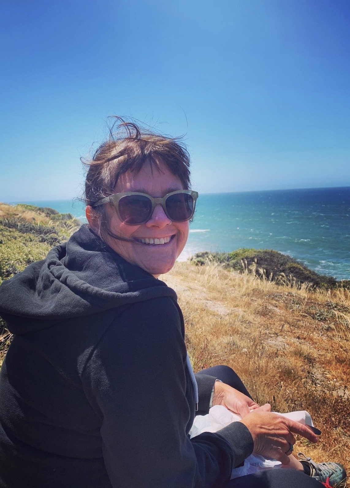 Kim Laidlaw smiling at the camera on a sunny day by the ocean